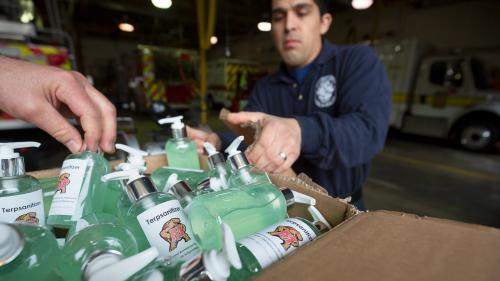 Firefighters Oscar Montalvo ’10, right, and Tyler Maccrone, hand at left, open a box of “Terpsanitizer,” hand sanitizer created by professors and students in the Department of Chemical and Biomolecular Engineering and donated to the Gaithersburg-Washington Grove Volunteer Fire Department. (Photos by Stephanie S. Cordle)