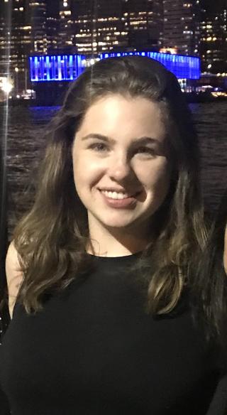 A headshot of Erin Tinney. She is smiling with a city skyline in the background.