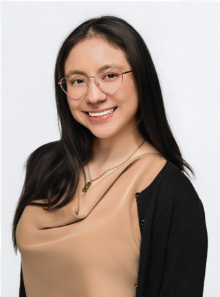 woman with dark hair and glasses in a tan shirt smiling